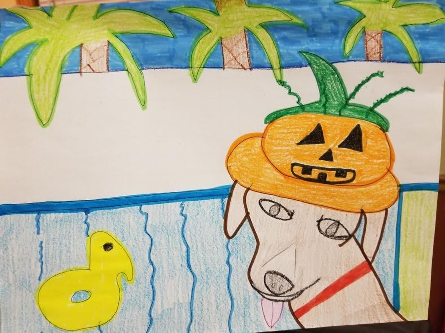 This is an image of a drawing made with markers and colored pencils. A light brown dog sits in front of a pool. The dog is wearing a silly jack-o-lantern hat. The dog is sticking its tongue out and has a red collar. A yellow duck floaty is in the pool. Behind the dog and the pool is a white wall. Palm trees can be seen sticking up from behind the wall. The sky is blue. Jess Ramirez